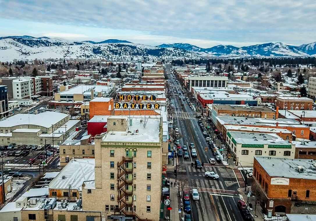 Aerial View of Downtown Bozeman with Baxter Hotel Aerial View of Main Street in downtown Bozeman Montana. Winter snow is scattered on streets and buildings with the mountain range covered in snow in the distance. Famous Baxter Hotel Sign is seen up close.